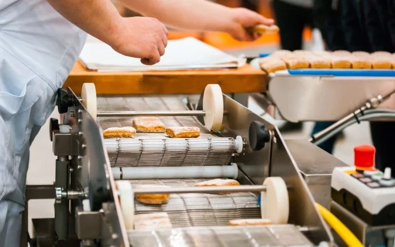 A production line in a confectionary factory with an employee overseeing the machinery.