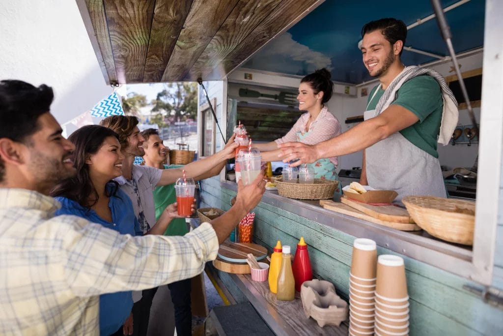 A couple orders food at the window of a food truck.