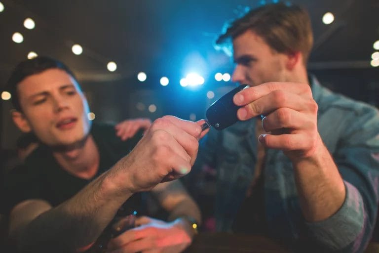 A man takes car keys from an intoxicated friend.