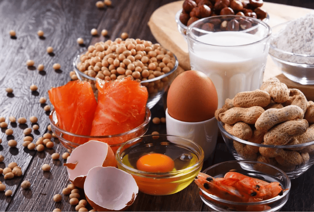 A picture depicting several types of foods that are common allergens, including eggs, peanuts, milk, and flour.