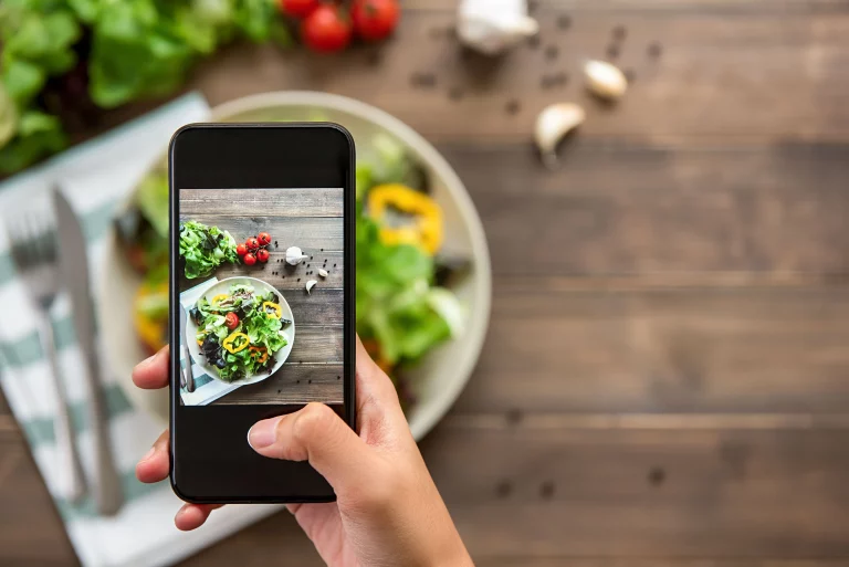 : A group of people take overhead pictures of their food with their cell phones at a restaurant.