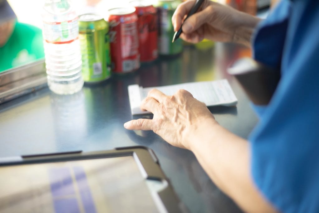 A close-up shot of a food truck cashier taking orders on an iPad and a paper ticket.