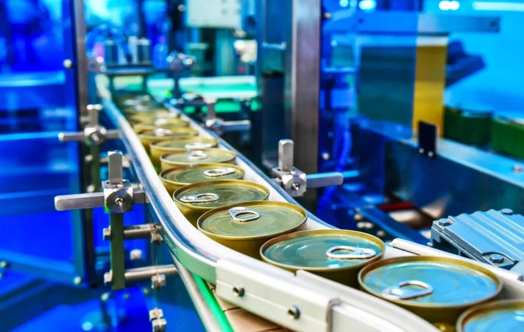 A factory conveyor belt with canned goods.