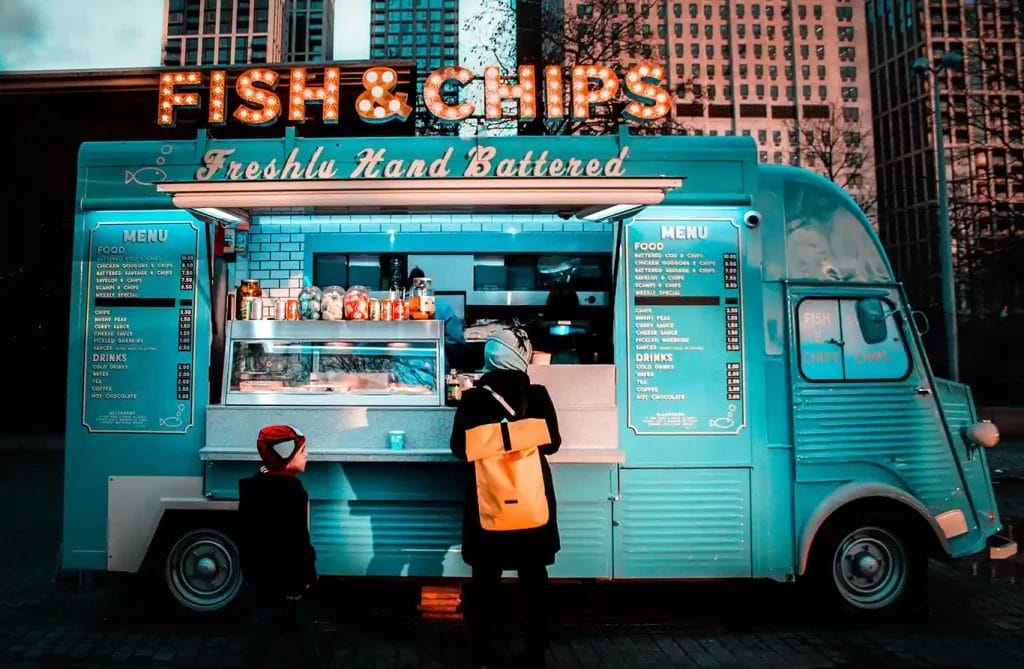 A blue food truck with a marquee that reads "Fish & Chips" on top.
