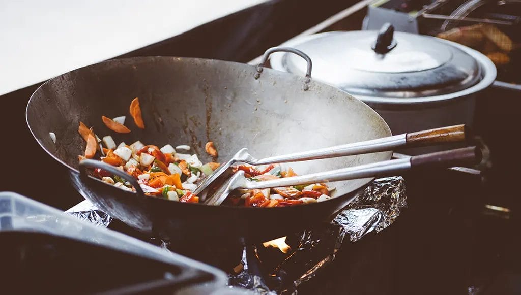 Assorted vegetables being cooked in a large wok