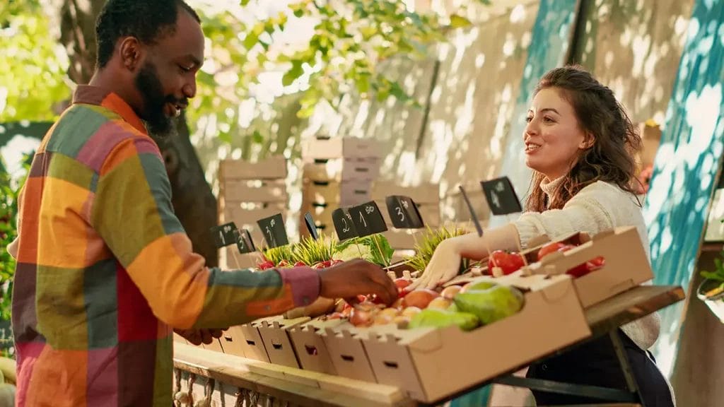 Person assisting customer at farmers market stand.