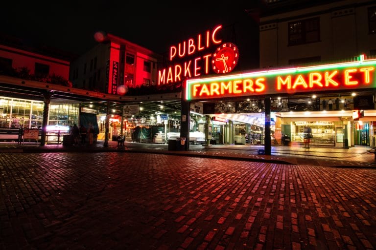 A picture of Pike Place Market in Seattle at night with neon signs lit.