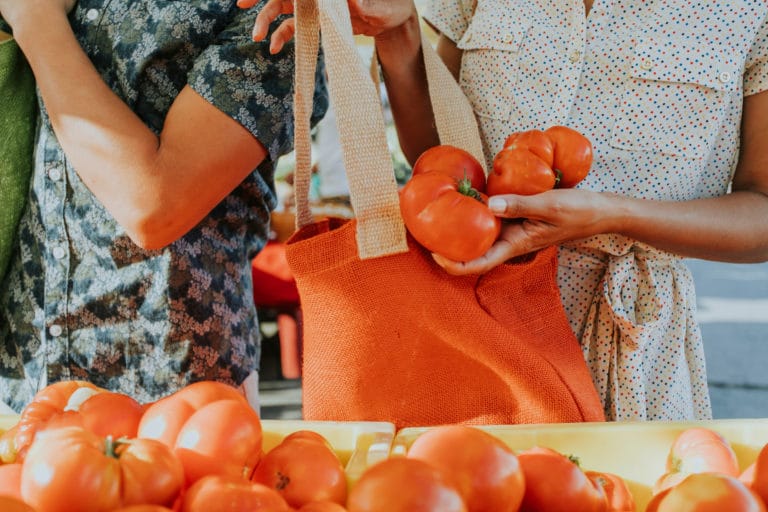 Friends buying fresh tomatoes at a farmers market