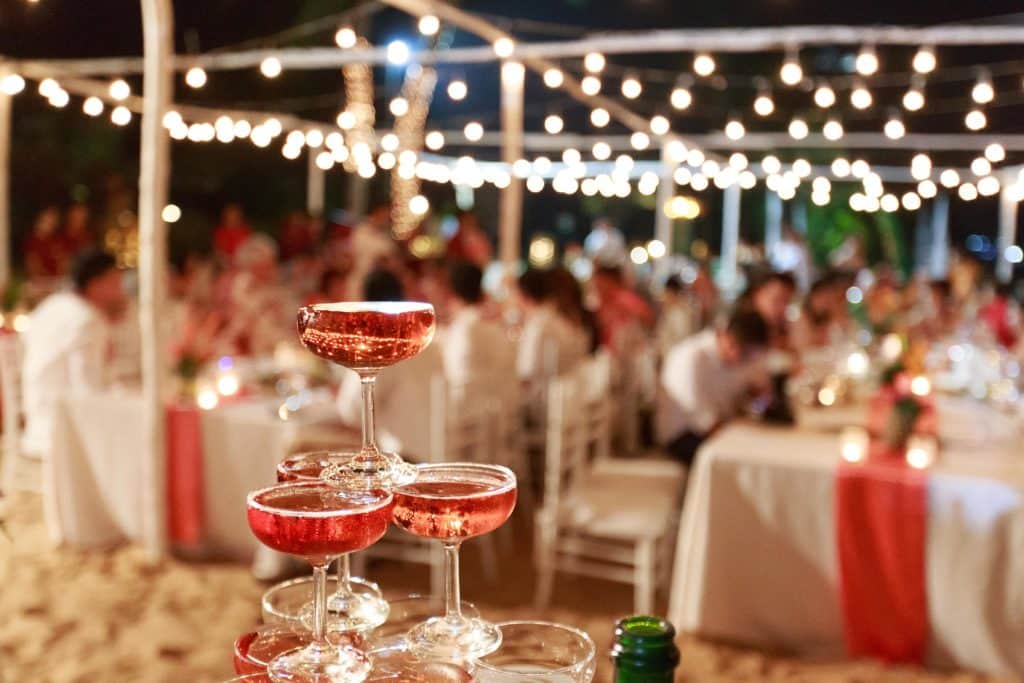 Wine glasses on a table with wedding party in the background.