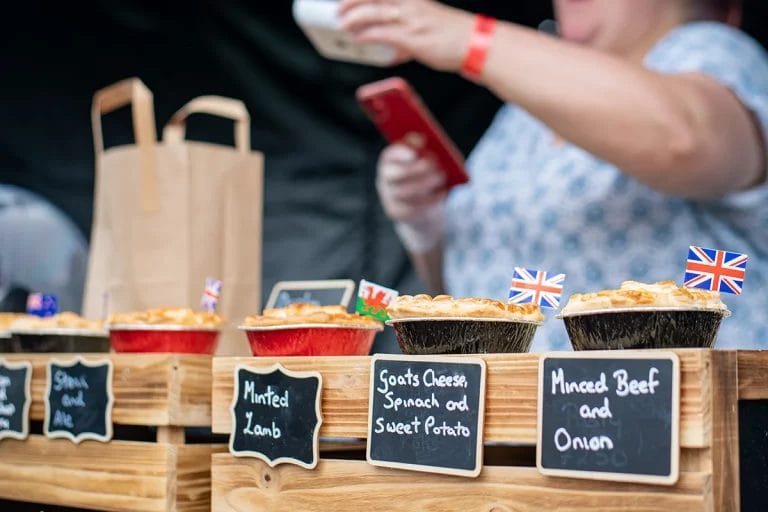 British pies sold at a market with small chalkboard signs.