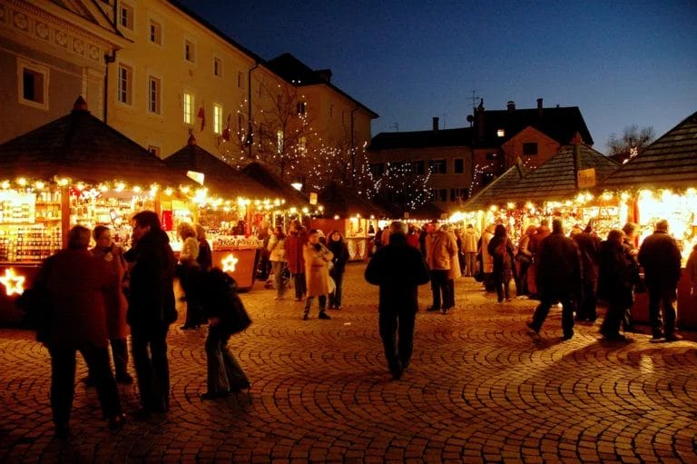 A winter farmers market at night illuminated by string lights.