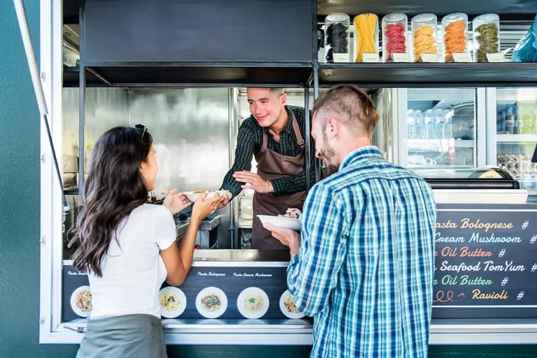 A couple buys pasta from a food truck.