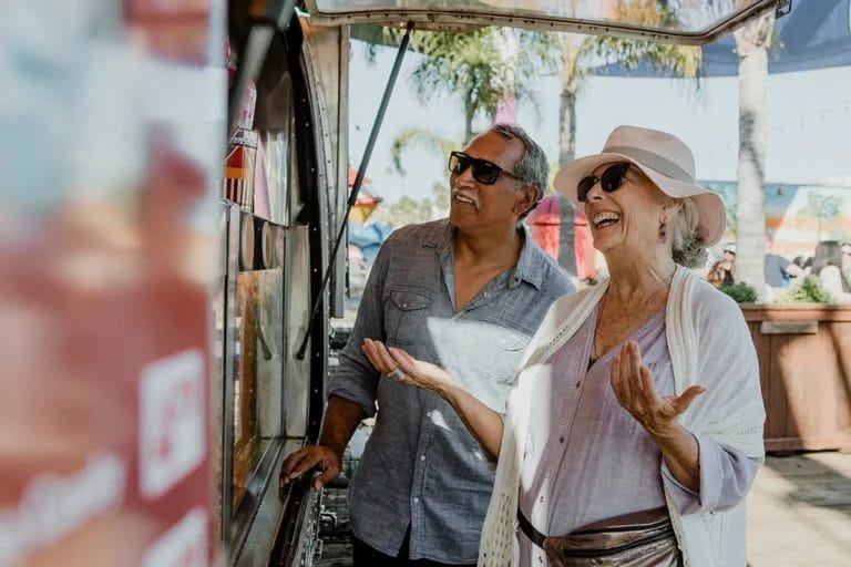 An elderly couple order from a food truck on a sunny day in California.