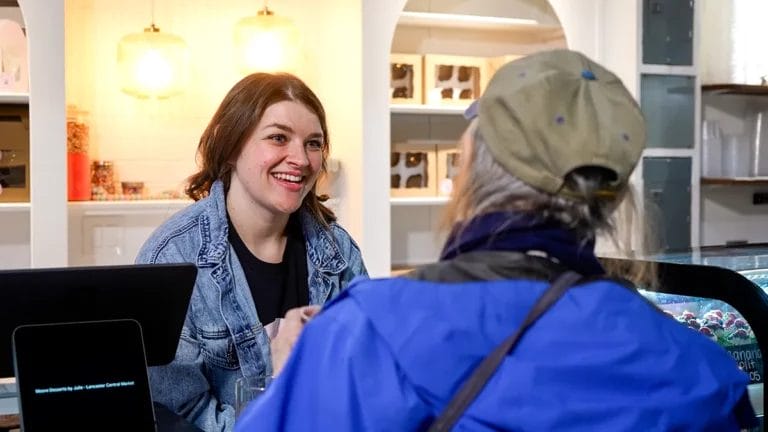 Lauren Moore smiles at a customer as she takes their order at her mother's Lancaster Central Market stand, Moore Desserts by Julie.