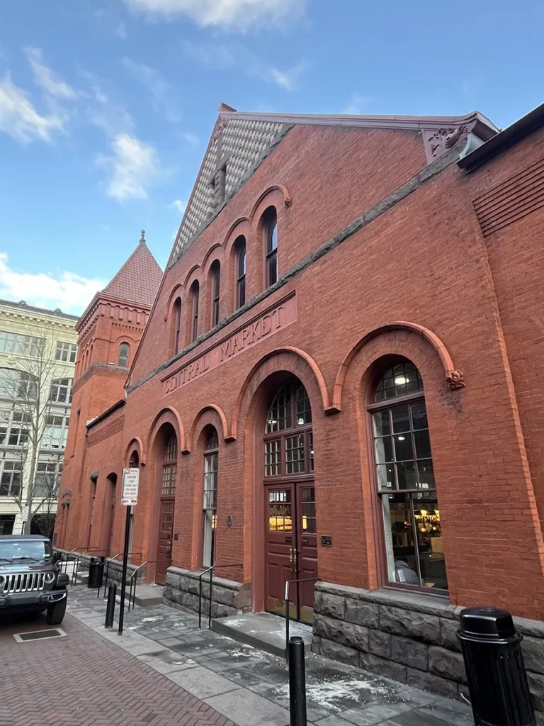 The facade of a red brick building reading "Central Market" and surrounded by patches of melting snow.