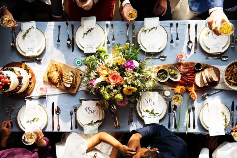 A bird's eye view of a table at a wedding showing an elaborate tablescape complete with food, drinks, and place settings for the bride and groom.