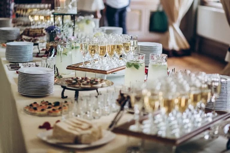 A buffet table at a wedding with champagne glasses, infused water, and appetizers.