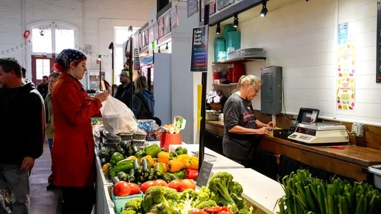 A customer bags produce at the Charles Family Farms booth at Lancaster Central Market.