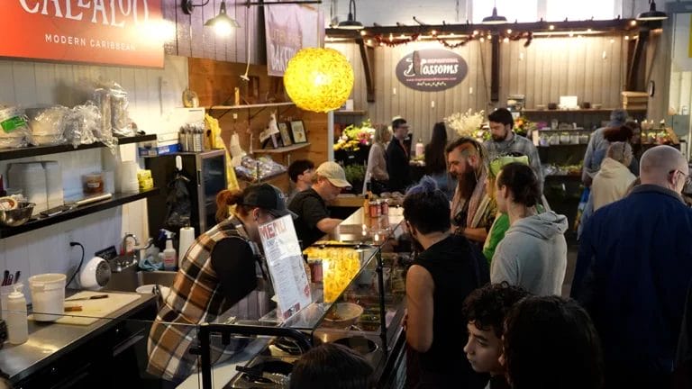 Workers at Callaloo's stand in Lancaster Central Market prepare food for customers during a busy market day.