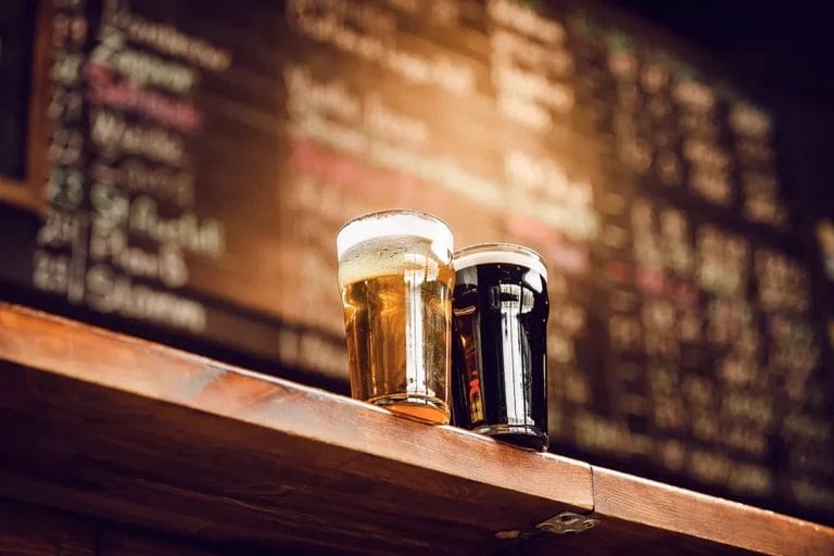 Two craft beers on a table in front of a menu at a brewery.