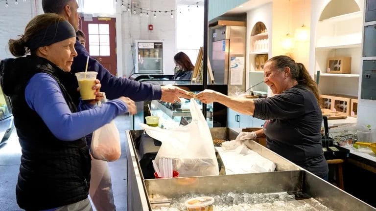 A worker at Charles Family Farm's booth takes cash from a customer after bagging oranges and eggs for them.