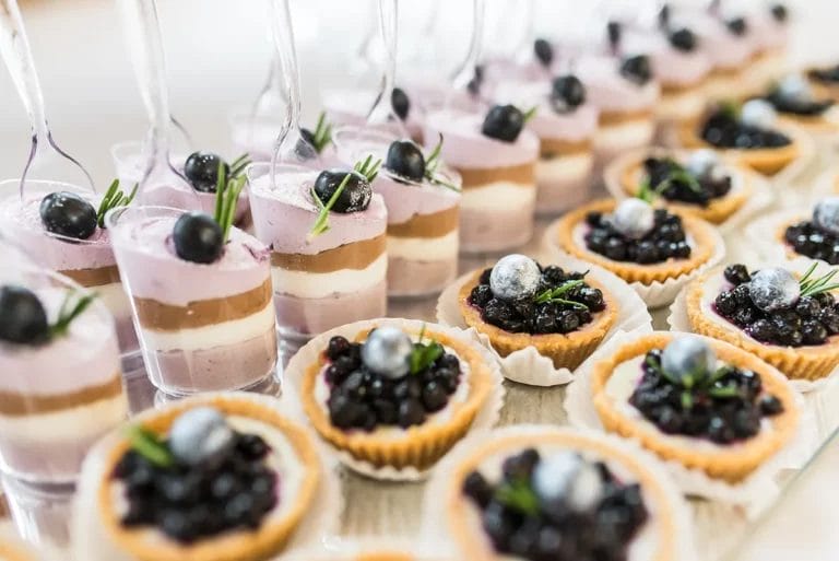 A catering spread of blueberry tarts and blueberry parfaits.