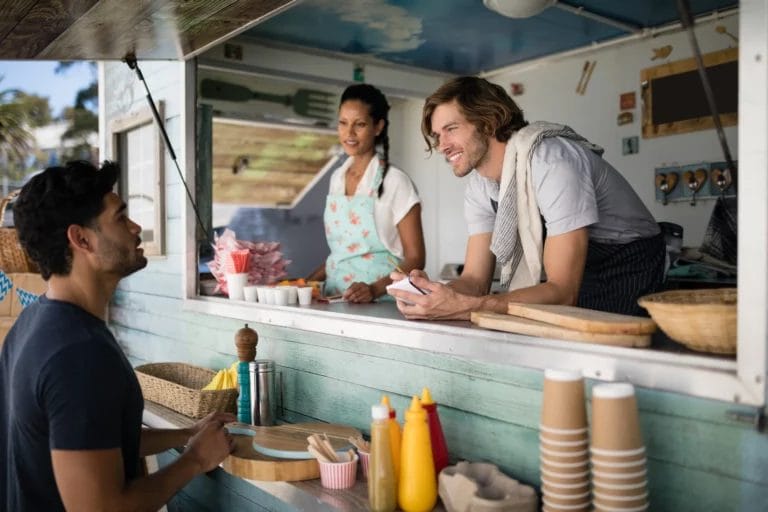 Two food truck workers serve a customer