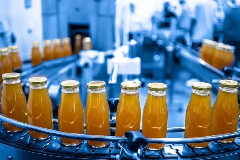 A production line in a factory producing juice in glass bottles on a conveyor belt.
