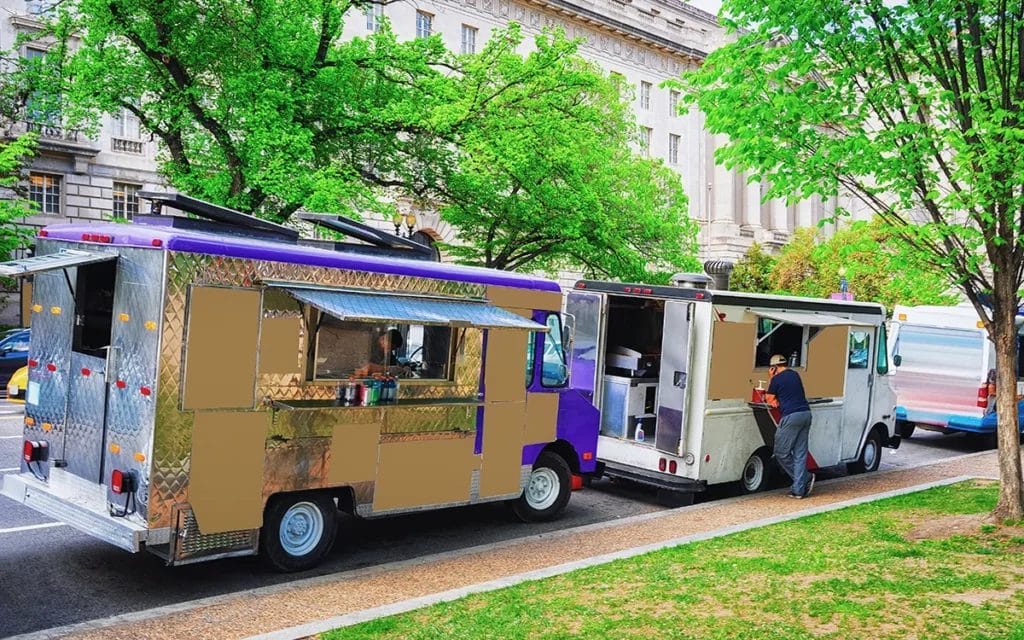 Two food trucks parked along a brick sidewalk on a street in Washington, D.C.