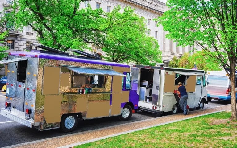 Two food trucks parked along a brick sidewalk on a street in Washington, D.C.